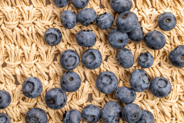 Several ripe blueberries, close-up,  on a straw mat, top view.