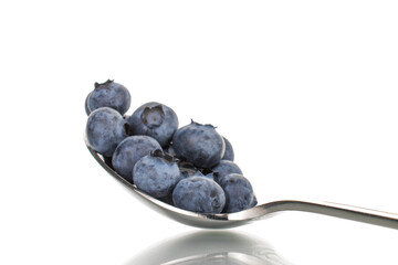 Several berries of ripe dark purple blueberries with a metal spoon, close-up, isolated on white.