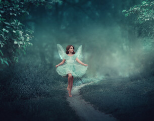 Fototapeta na wymiar A girl with fairy wings runs through a fairy forest. Around the girl is a dark foggy forest. The girl has glitter wings. She is dressed in blue
