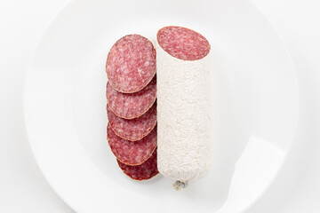 White plate with sliced salami sausage. Top view.