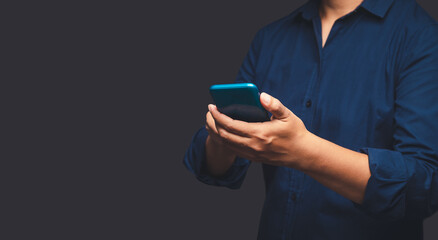 Close-up of hands businessman in a suit using a mobile phone while standing on a gray background.