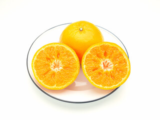 Top view of oranges cut half and whole on a white dish over a white background