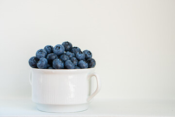 Water drops on ripe blueberries in small white dish