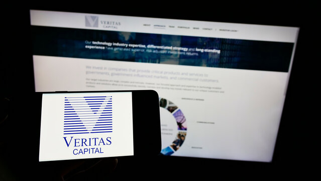 Stuttgart, Germany - 01-16-2022: Person holding cellphone with logo of American company Veritas Capital Fund Management LLC on screen in front of webpage. Focus on phone display.