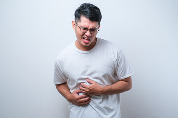 Young handsome Asian man wearing casual shirt and glasses getting stomach ache or getting abdominal...
