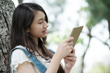 Young Asian teenage girl with tablet and notebook