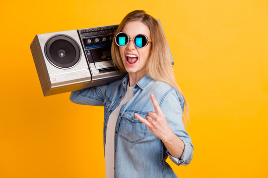 Photo of girl hold boom box show rock roll sign wear youth style clothes isolated over yellow color background