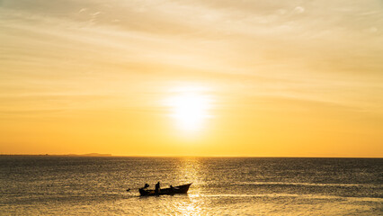 Naklejka premium Sunset sky clouds over sea in the evening with orange sunlight and traditional fishing boat 