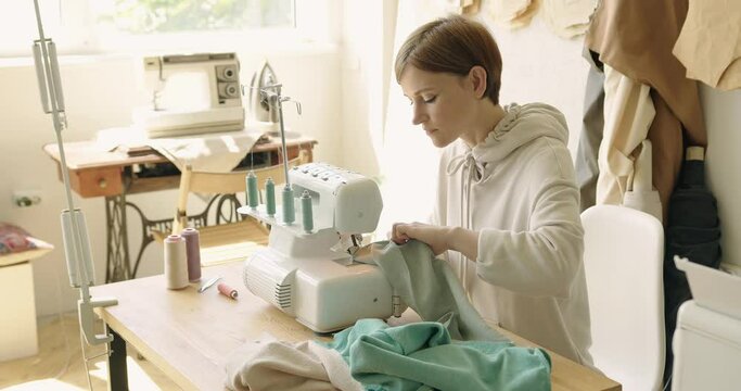 Woman seamstress creating new clothes in sewing studio. Dressmaker working