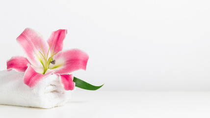 White towel and pink lily with copy space banner, spa minimal background