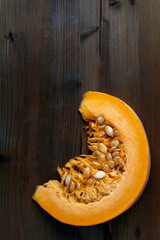 Fresh organic pumpkin slice with seeds on a dark wooden background