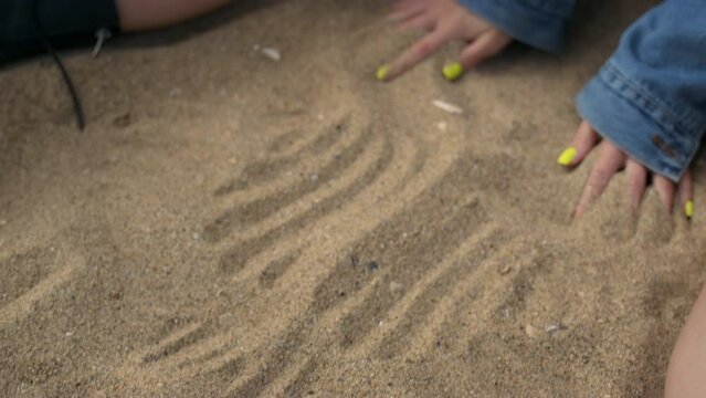 Unknown girl hands drawing lines on beach sand close up. Lady enjoy nature.