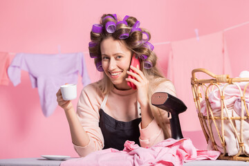 A woman is on the phone with a friend gossiping while sipping coffee, a break from household...