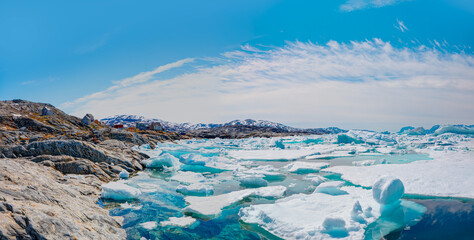 Melting icebergs by the coast of Greenland, on a beautiful summer day - Melting of a iceberg and pouring water into the sea - Tiniteqilaaq, Greenland