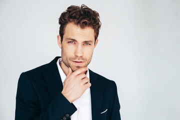 Closeup portrait of handsome confident stylish hipster lambersexual model. Sexy modern man dressed in black elegant suit. Fashion male posing in studio. Touching his chin