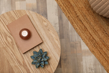 Book, candle and decor on round wooden table indoors, top view