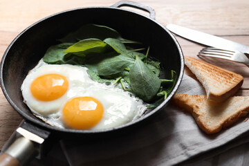 Delicious fried egg with spinach served on wooden table, closeup
