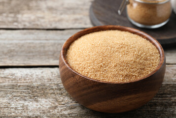 Brown sugar in bowl on wooden table. Space for text