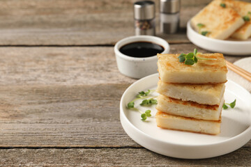 Delicious turnip cake with microgreens served on wooden table. Space for text