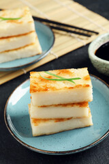 Delicious turnip cake with herb on black table, closeup
