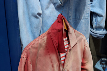 Faded red Breton jacket with collar turned up, hanging from faded blue jacket
