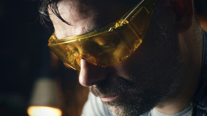 Exhausted worker in protective goggles and gloves after processing metal products for his small...