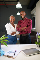 Two Black co-founders pose at their office desk with arms crossed