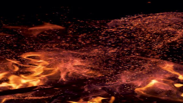VERTICAL SLOW MOTION, MACRO, DOF: Sparks flying around the branches in the blazing campfire. Glowing particles popping out of a bonfire lit up in the pitch black wilderness on a tranquil summer night.