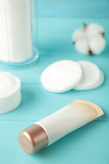 Cream package with cotton pads in container on blue background. Beauty skincare products. Vertical photo.