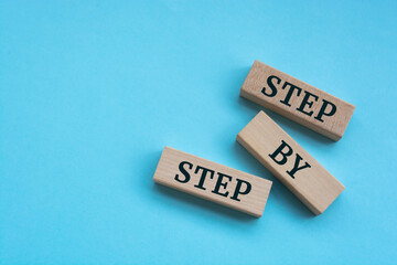 Wooden blocks with words 'step by step'.