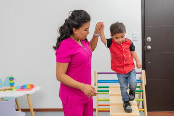 Nurse helping a child walk through a wooden game, which is in her medical office