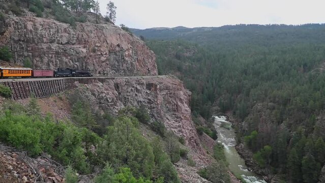 Antique train on the side of a cliff next to the anima river