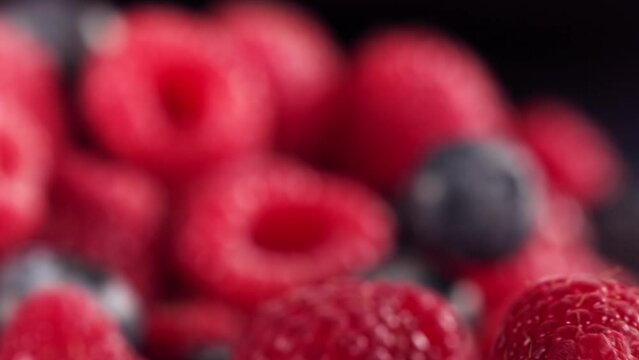 Ripe juicy Raspberry and Blueberry rolling above many Raspberries and Blueberries