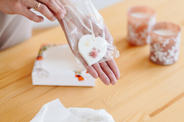 Fototapeta na wymiar White Florentine Sachet In Shape Of A Heart With Flowers Dried Flowers In Women's Hands.