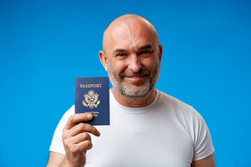 Middle age man holding passport with a happy face against blue background