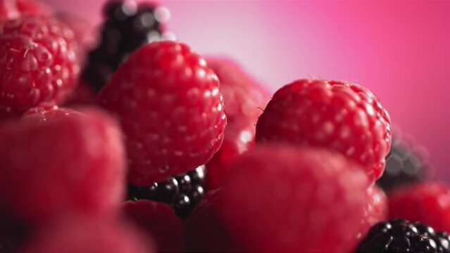Ripe juicy Raspberry rolling above many Raspberries and Blackberries