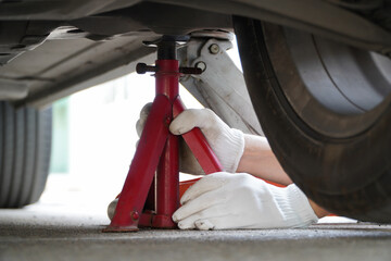 white gloved mechanic is using a jack to stand up safely in your car