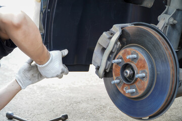 Asian mechanic installs new plastic wheel arches,mechanic worker working using cross wrench tool for repair,Service by skilled technicians checking the car under the car in the garage
