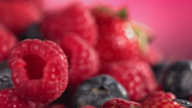 Ripe juicy Strawberry Blueberry Raspberry rolling above many mixed Berries