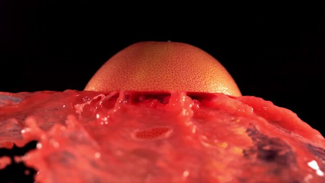 Fresh Grapefruit fruit squirting and burst with juice in slow motion in black background 4K