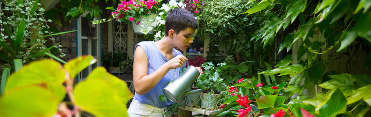 Young woman watering plants in her summer garden