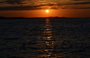 Sol cayendo detras de las montañas sobre el mar mediterraneo