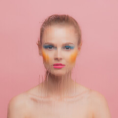 Portrait of beautiful young woman with bright makeup posing isolated over pink studio background....