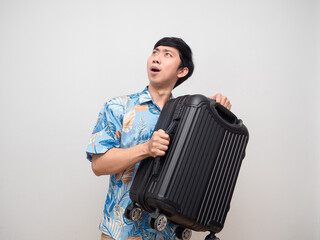 Young man beach shirt holding laggage feels excited looking up