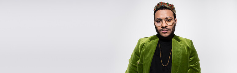 eastern hip hop performer in green velvet blazer and crown isolated on grey, banner.