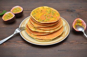 stack of pancakes with passion fruit on wooden background