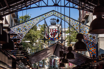 Indoor detail of the famous Food Market (La Boqueria) in the old town of Barcelona, Catalonia, Spain, Europe. Colorful patterns and ornaments on glass. Grand iron entrance the way up the Las Ramblas. - obrazy, fototapety, plakaty