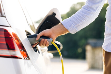 The driver of the electric car inserts the electrical connector to charge the batteries....