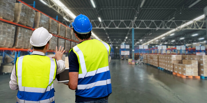 Rear View Group Of Worker Standing And Checking Large Retail Warehouse Logistics, Distribution Center With Computer. Multiethnic Business Manager Looking In Future With Warehouse Building.