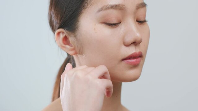 Portrait young Asian woman touching perfect neck skin over grey background